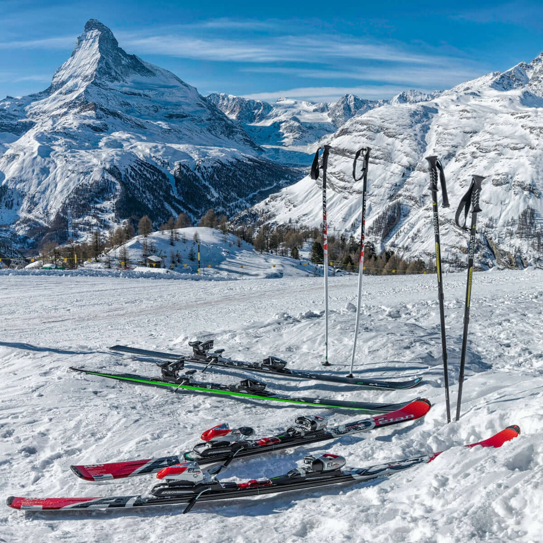 two pairs of red and green skis near mountain covered by snow at daytime