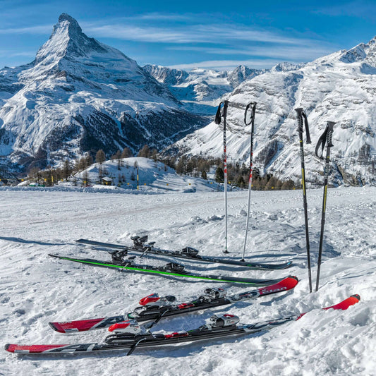 two pairs of red and green skis near mountain covered by snow at daytime