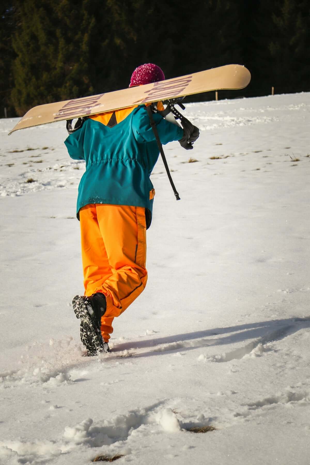A person walking in the snow with a snowboard on their head