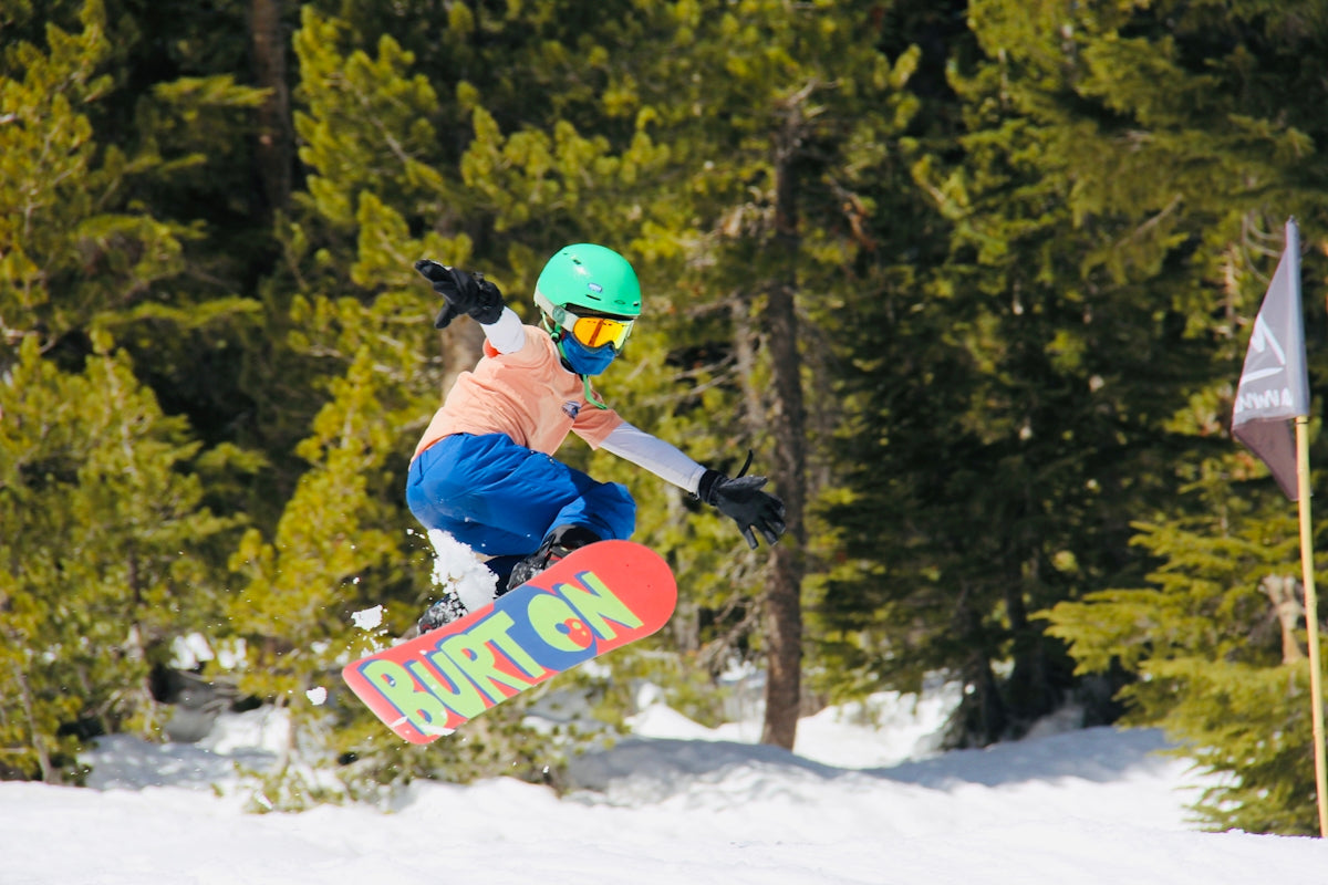 man in blue jacket and red helmet riding red snowboard on snow covered ground during daytime