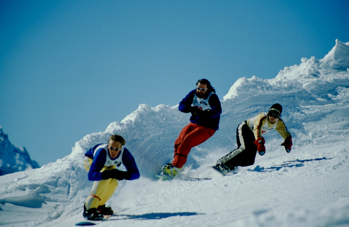 2 person in red and white snow suit riding on snow board during daytime