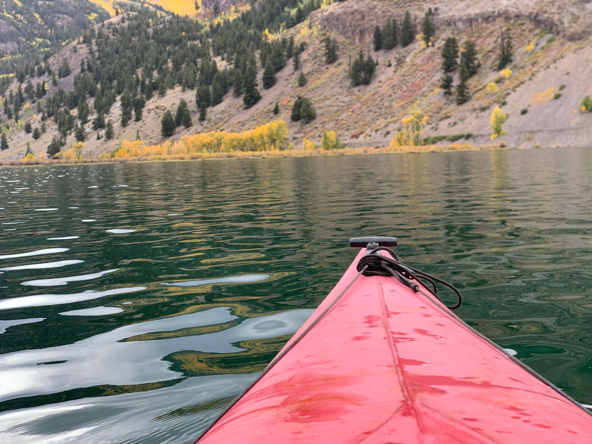 a red kayak in the water with mountains in the background