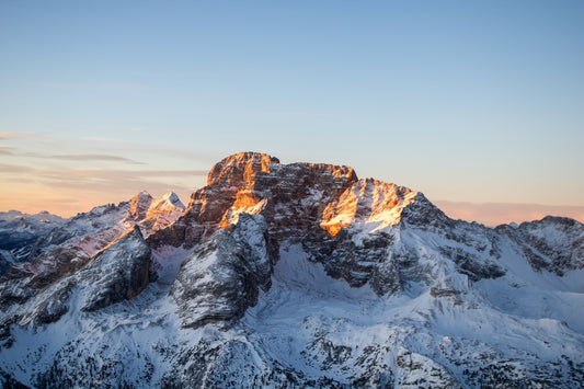Snowy mountain range lit by sunrise.