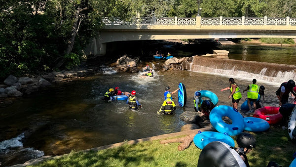 Group launching tubes into Boulder Creek with helmets and life jackets