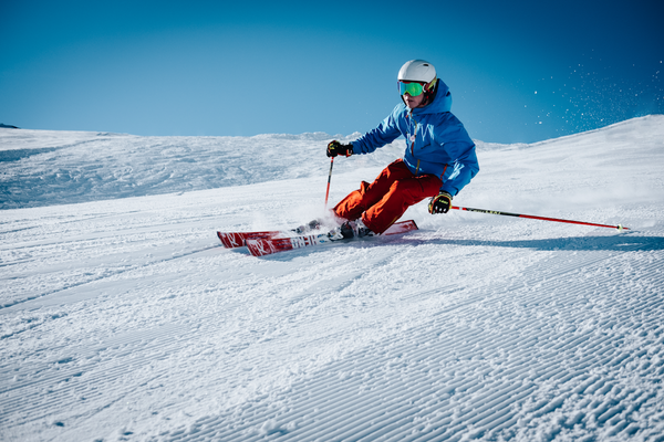 Skier carving aggressive turn on groomed slope