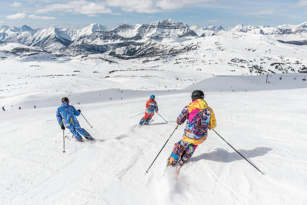 Group of skiers on groomed run with mountain panorama